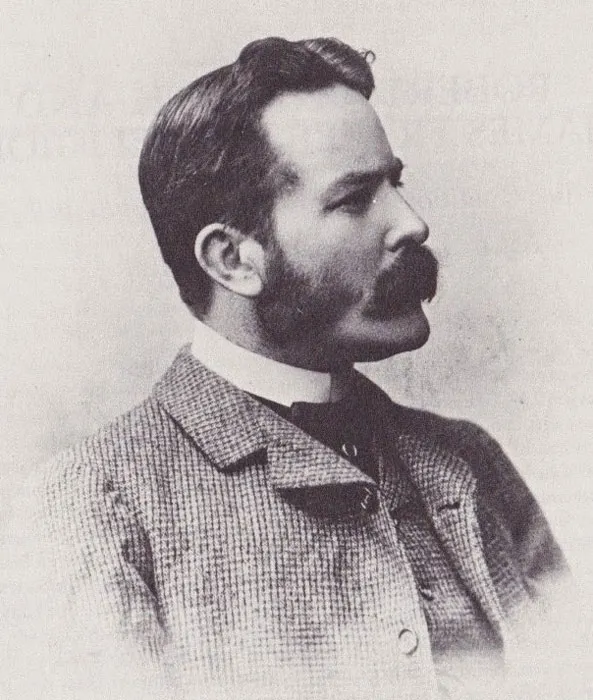 Retrato antiguo a blanco y negro de un joven James George Frazer, luce un bigote exuberante y viste un saco a cuadros, on un patron conocido como escocés.